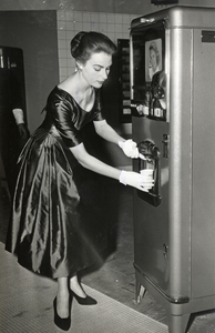 501366 Afbeelding van een dame in een satijnen jurk die een koffieautomaat demonstreert op de Jaarbeurs te Utrecht.